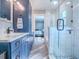 This bright bathroom features a glass-enclosed shower, blue vanity with granite countertop, and an ensuite view of the bedroom at 111 Cardinal Ln, Eustis, FL 32726