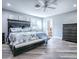 Bedroom with wood-look flooring, a queen sized bed, ceiling fan, plus view into an en suite bathroom at 111 Cardinal Ln, Eustis, FL 32726