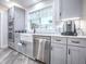 Kitchen with stainless steel appliances, farmhouse sink, granite countertops, tile backsplash, and white shaker style cabinets at 111 Cardinal Ln, Eustis, FL 32726