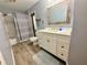 Updated bathroom featuring modern vanity with marble countertop, decorative mirror, tub and shower with grey curtain at 11301 Via Mari Cae Ct, Clermont, FL 34711