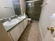Bathroom with double sink vanity, tile floor, and modern shower with glass doors at 11301 Via Mari Cae Ct, Clermont, FL 34711