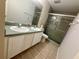 Bathroom featuring double sink vanity with white cabinetry, ceramic tile flooring, and a glass-enclosed shower at 11301 Via Mari Cae Ct, Clermont, FL 34711