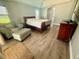 Bright bedroom featuring hardwood floors, a cozy chair with ottoman, and a comfortable queen-size bed at 11301 Via Mari Cae Ct, Clermont, FL 34711