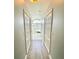 A hallway leading to a bathroom featuring an arched window and white tile flooring at 11301 Via Mari Cae Ct, Clermont, FL 34711