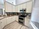 Kitchen featuring white cabinets, stainless steel appliances, and hardwood flooring, offering modern amenities at 11301 Via Mari Cae Ct, Clermont, FL 34711