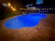 Inviting in-ground pool illuminated with vibrant blue lights for evening swims and relaxation at 11301 Via Mari Cae Ct, Clermont, FL 34711
