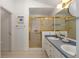 Bathroom boasts double sinks, gold hardware, tiled floors, and a shower with glass doors at 1305 Santa Maria Ave, The Villages, FL 32159