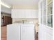 Well-equipped laundry room with ample storage, utility sink, and convenient access to the garage at 1305 Santa Maria Ave, The Villages, FL 32159