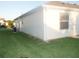 Side view of a well-maintained home with vinyl siding, a small window and lush green lawn at 1310 Jimenez Ct, The Villages, FL 32159