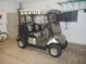 Close-up of a well-maintained golf cart with a striped roof parked inside the home garage at 1310 Jimenez Ct, The Villages, FL 32159