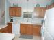 Bright kitchen features oak cabinets, white appliances and countertops and light blue paint at 1310 Jimenez Ct, The Villages, FL 32159
