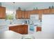 Bright kitchen features oak cabinets, white appliances and countertops and light blue paint at 1310 Jimenez Ct, The Villages, FL 32159