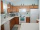 Bright kitchen features oak cabinets, white appliances and countertops and light blue paint at 1310 Jimenez Ct, The Villages, FL 32159