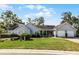 Well-maintained home with a two-car garage, mature trees, green lawn, and inviting front porch at 1350 Mosswood Dr, Leesburg, FL 34748