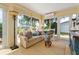 Cozy sunroom with large windows, comfortable sofa, and scenic backyard views at 1446 Arbor Trl, The Villages, FL 32162