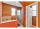 Bright bathroom offers a bathtub and a glass shower with an orange colored wall at 15322 Veramonte Way, Orlando, FL 32828