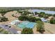 Scenic aerial view of community amenities including a pool and tennis courts near a lake and wooded area at 16211 Oak Breeze Ct, Clermont, FL 34711
