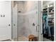 Elegant shower with glass door, wooden bench and attached walk-in closet at 16211 Oak Breeze Ct, Clermont, FL 34711