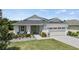 Inviting single-story home with a manicured lawn, beautiful garden, and a charming front entrance at 16211 Oak Breeze Ct, Clermont, FL 34711