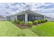Large screened patio with an adjacent backyard with a well manicured lawn and privacy bushes at 2129 Landrea Loop, The Villages, FL 32163