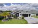 Charming home with a well-manicured lawn, colorful flowers, and a gray driveway with a palm tree emblem at 2129 Landrea Loop, The Villages, FL 32163
