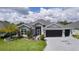 Lovely single-story home with well-maintained lawn, landscaping, and a dark gray driveway featuring a palm tree emblem at 2129 Landrea Loop, The Villages, FL 32163