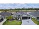 Beautiful home with a well-kept lawn, a dark gray driveway with a palm tree, and water views in the background at 2129 Landrea Loop, The Villages, FL 32163
