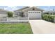 Charming home exterior with a well-manicured lawn, white picket fence, and attached garage at 2296 Whisper St, The Villages, FL 32162