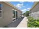 Property side yard with walkway, green bushes and a large sliding glass door at 2296 Whisper St, The Villages, FL 32162