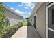 Side yard with a walkway leading to a yard with green grass and clear blue skies at 2296 Whisper St, The Villages, FL 32162