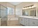 Elegant bathroom with double vanity, soaking tub, and glass-enclosed shower at 24346 Amberleaf Ct, Leesburg, FL 34748