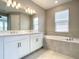 Bright bathroom with a double sink vanity, large mirrors, bath tub, and modern finishes at 2675 Ridgetop Ln, Clermont, FL 34711