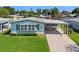 Single-story home with covered parking, landscaped yard, and an American flag at 3026 Myakka River Rd, Tavares, FL 32778