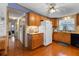 A kitchen featuring wood cabinets, appliances, a tiled backsplash, and hardwood floors that flow into the hall at 3026 Myakka River Rd, Tavares, FL 32778