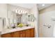 Bright bathroom featuring a granite-topped double vanity, large mirror, and separate tiled walk-in shower at 3041 Batally Ct, The Villages, FL 32162