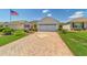 Inviting single-story home with a brick-paved driveway, attached garage, and well-maintained lawn at 3041 Batally Ct, The Villages, FL 32162