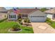 Charming home exterior with landscaped front yard, brick driveway, and attached garage at 3041 Batally Ct, The Villages, FL 32162