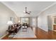 Bright living room with hardwood floors, ceiling fan, and a decorative door, with views of dining and kitchen at 3041 Batally Ct, The Villages, FL 32162
