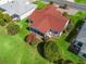Aerial view showcases the home's charming red roof, screened-in porch and manicured landscaping in a lovely neighborhood at 3266 Woodridge Dr, The Villages, FL 32162
