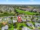 Aerial shot shows the home nestled in a charming community with lush greenery, a pond, and a golf course nearby at 3266 Woodridge Dr, The Villages, FL 32162