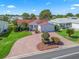 Aerial view of a well-maintained property showcasing a red roof, lush lawn, and a circular brick driveway at 3266 Woodridge Dr, The Villages, FL 32162