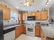 Traditional kitchen with oak cabinets, granite countertops, and modern black appliances at 3266 Woodridge Dr, The Villages, FL 32162