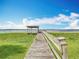 Wooden dock extends to the water, offering a serene escape with its covered area and picturesque waterfront views under a clear sky at 33620 Picciola Dr, Fruitland Park, FL 34731