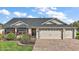 Charming single-story home featuring a well-manicured lawn, brick driveway and a two-car garage with white doors and dark accents at 342 Mccormick Ln, The Villages, FL 32162
