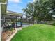 Exterior view of a home's backyard with a screened-in pool and well-manicured lawn at 3534 Auburndale Ave, The Villages, FL 32162