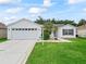 Inviting home featuring a two car garage, pristine lawn, blue shutters and solar panels for energy efficiency at 3534 Auburndale Ave, The Villages, FL 32162