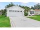 Home with a large garage, new driveway, fresh lawn, landscaping and signpost at 3534 Auburndale Ave, The Villages, FL 32162