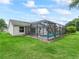 Back exterior view of a home with a screened-in pool and well-maintained green lawn at 3534 Auburndale Ave, The Villages, FL 32162