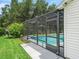 Home exterior showing screened-in pool with access door and walkway surrounded by green lawn at 3534 Auburndale Ave, The Villages, FL 32162