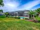 Expansive backyard featuring a screened-in pool, lush lawn, and tropical landscaping at 3775 Brantley Place Cir, Apopka, FL 32703